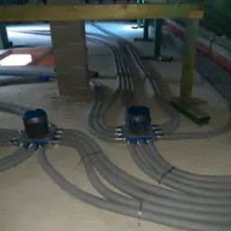 Rozprowadzenie szarych, elastycznych przewod&oacute;w wentylacyjnych z centralnymi rozdzielaczami pod stropem budynku w trakcie montażu rekuperacji.