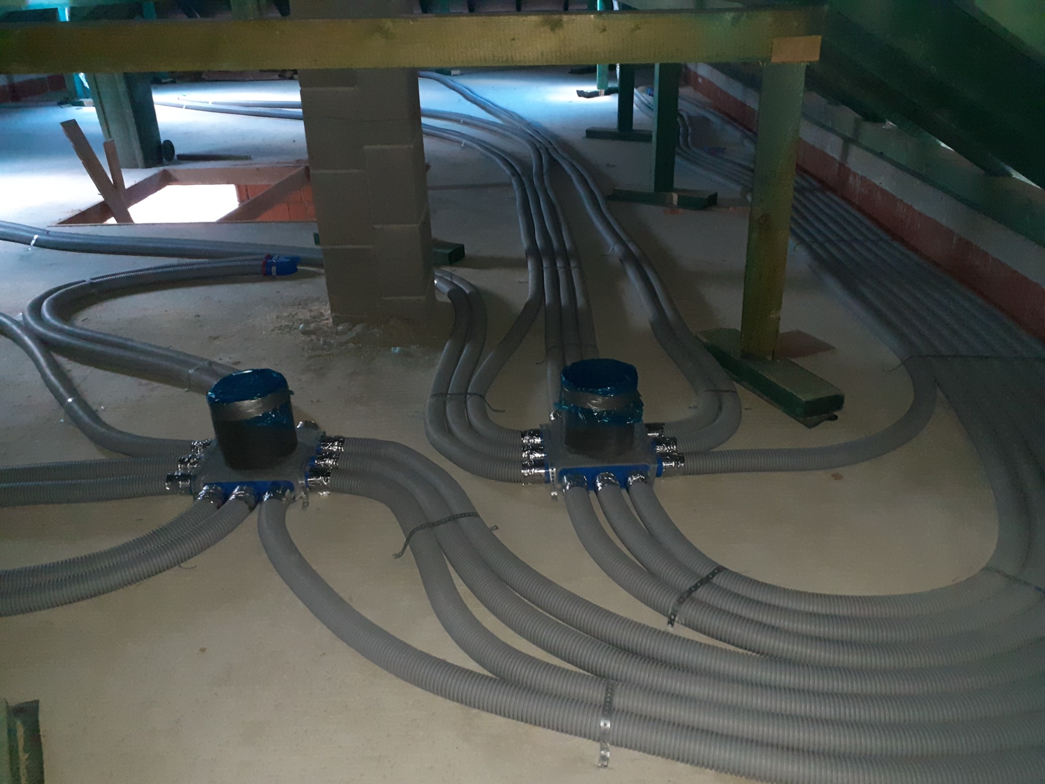 Rozprowadzenie szarych, elastycznych przewodów wentylacyjnych z centralnymi rozdzielaczami pod stropem budynku w trakcie montażu rekuperacji.