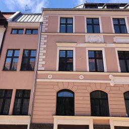 DAVLATBUD - Elewacja kamienicy w Bydgoszczy, zróżnicowana kolorystyka i detale architektoniczne, widok z dołu na fasady sąsiadujących budynków.