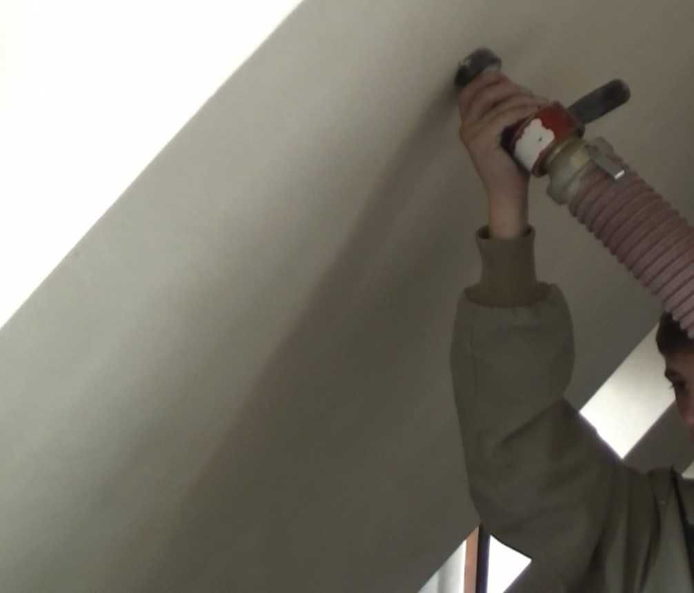 Ocieplanie poddasza pianką PUR w Paniówkach: aplikacja pianki z dyszy na skośną powierzchnię poddasza, widoczny fragment węża i operator w trakcie pracy.