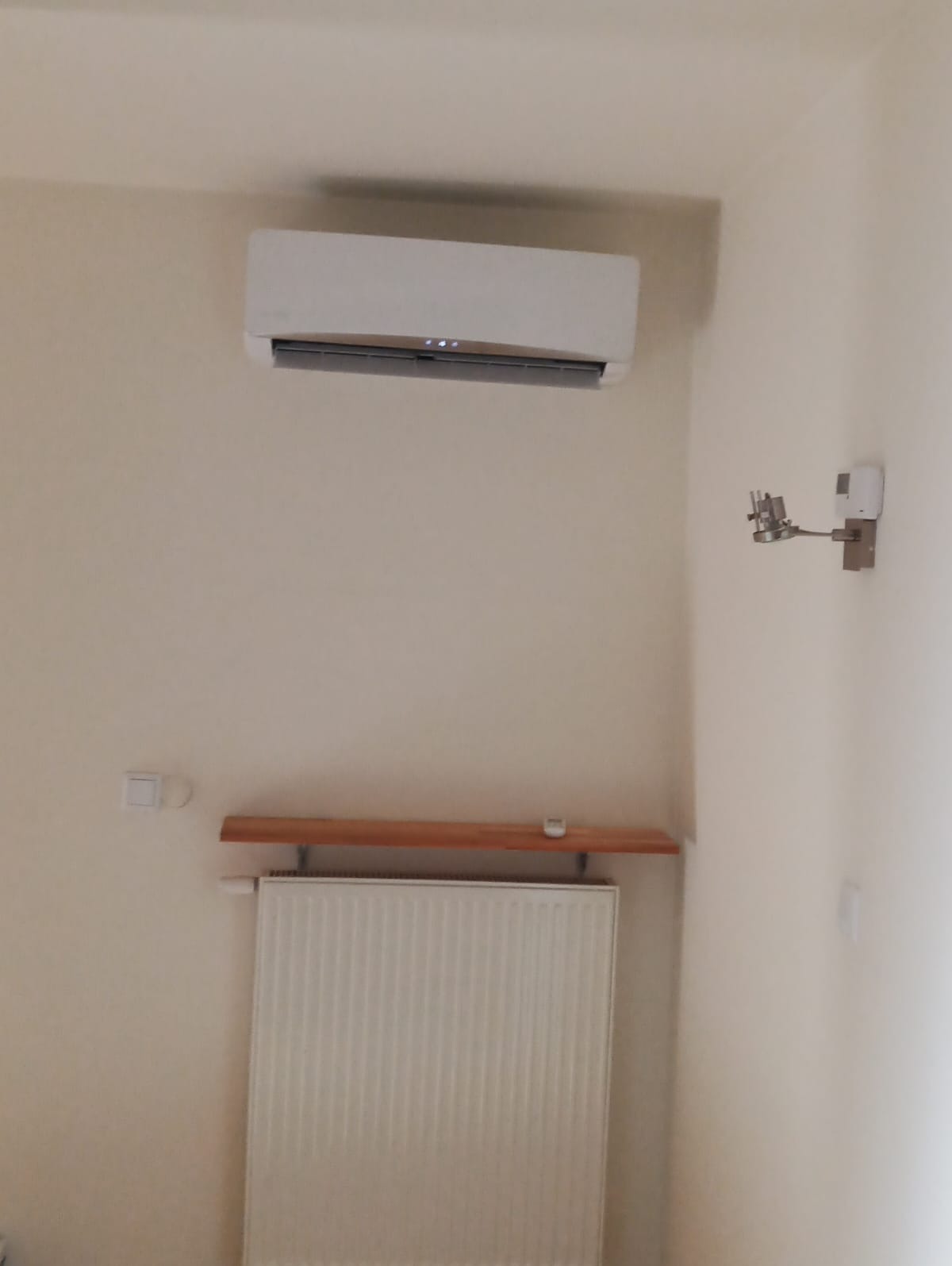 Zamontowany klimatyzator w domu w Zbychowie, widoczny również grzejnik pod półką.