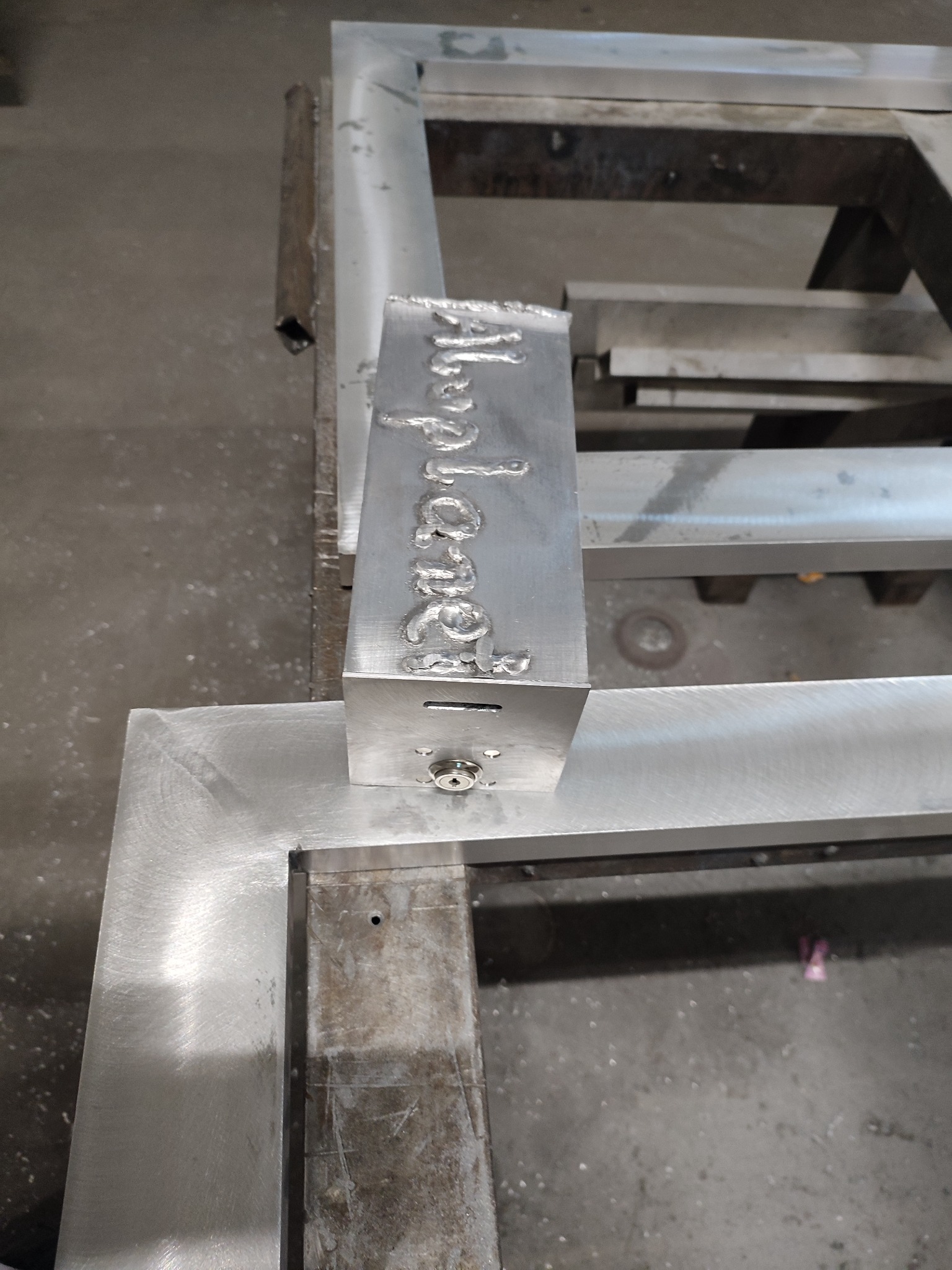 Spawanie napisu na metalowym elemencie konstrukcyjnym w warsztacie w Pińczowie. Widoczne ślady spawania i surowy metal.