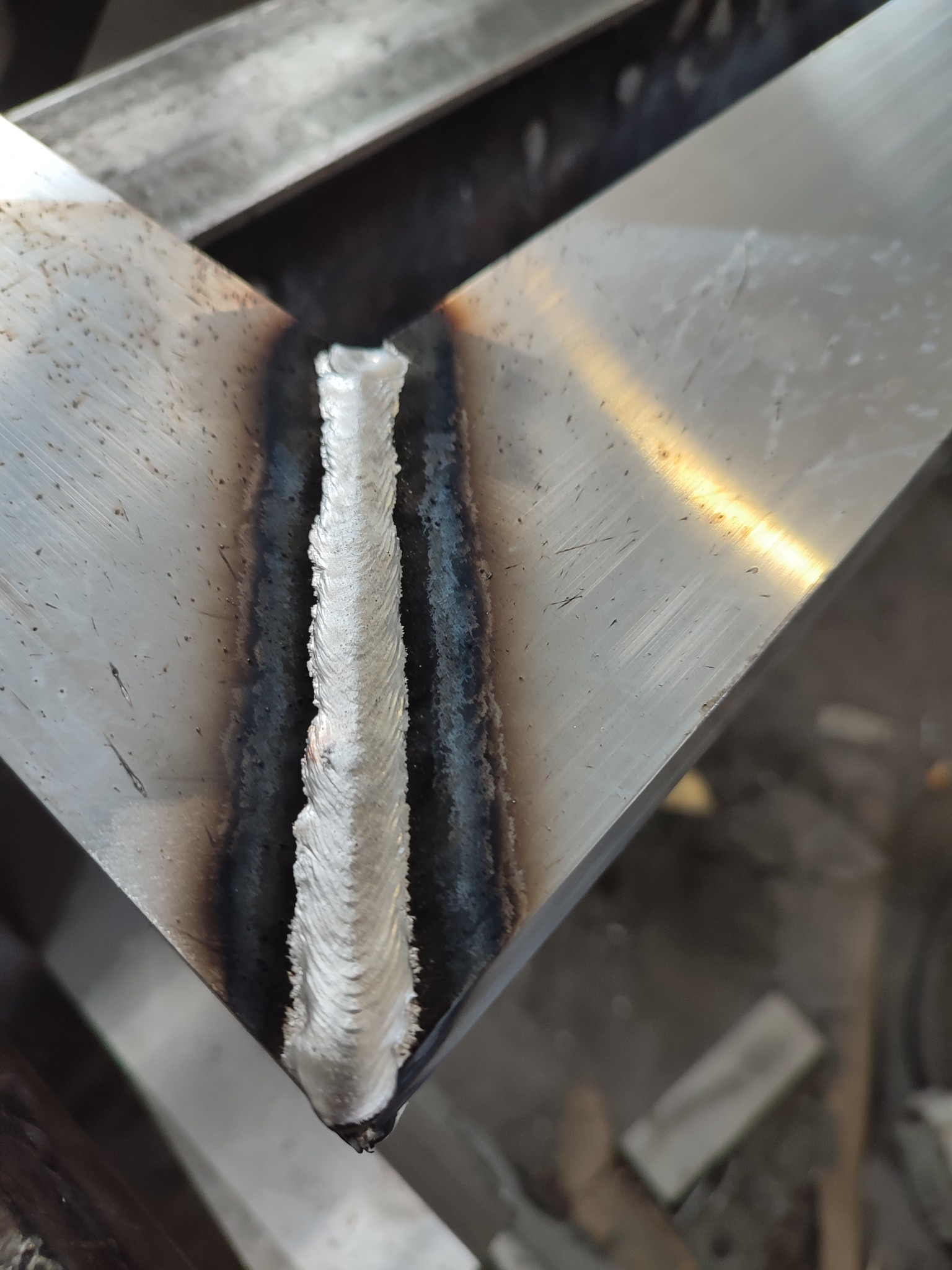 Metalowy profil kątowy połączony grubym spoiwem spawalniczym, widoczne ślady wysokiej temperatury.