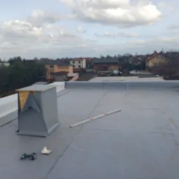 Membrana dachowa EPDM, narzędzia i komin wentylacyjny na płaskim dachu w Radlinie, w tle zabudowa jednorodzinna.