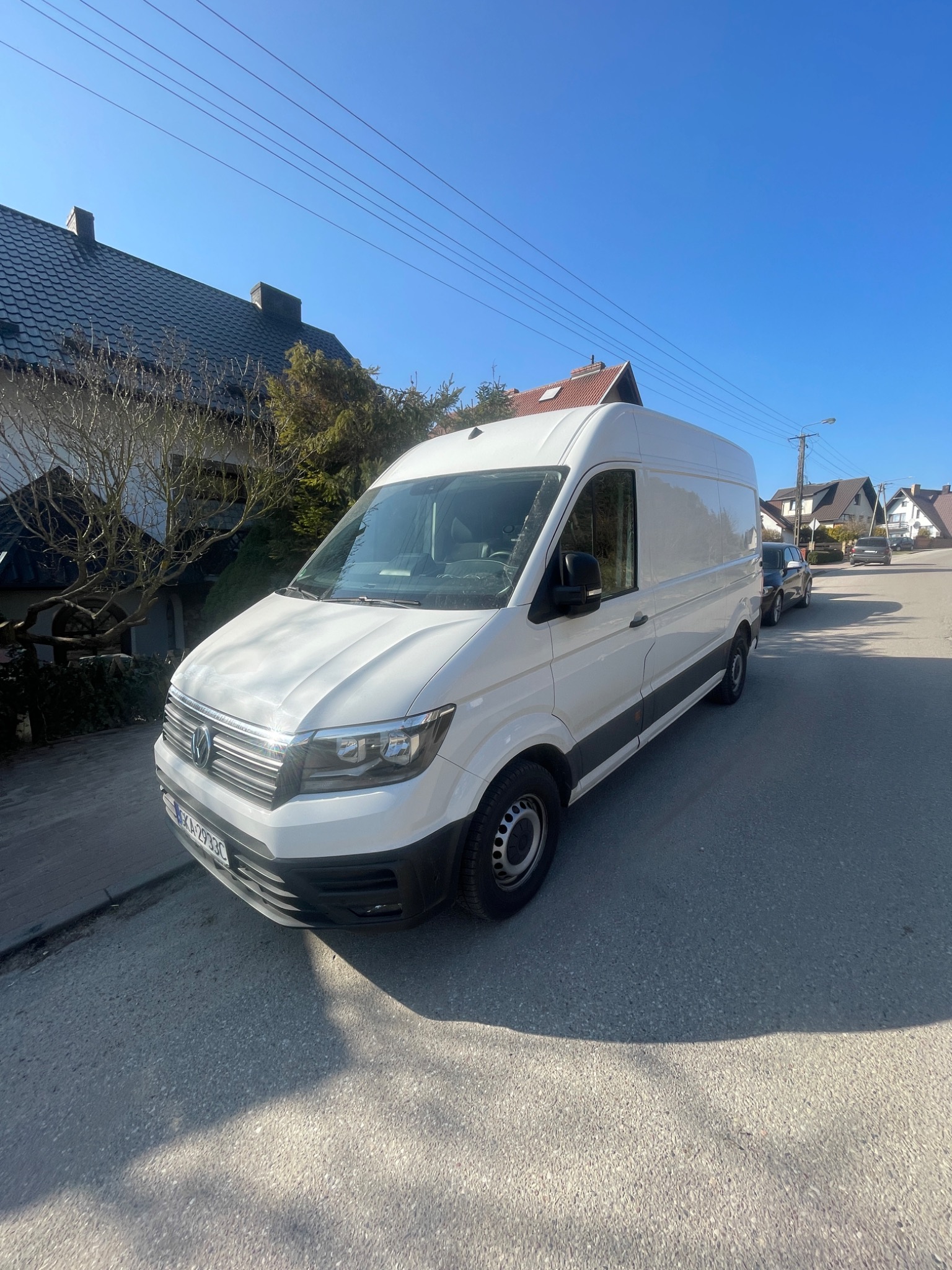 Biały samochód dostawczy Volkswagen Crafter zaparkowany na ulicy w słoneczny dzień, widoczny numer rejestracyjny KA2933C.