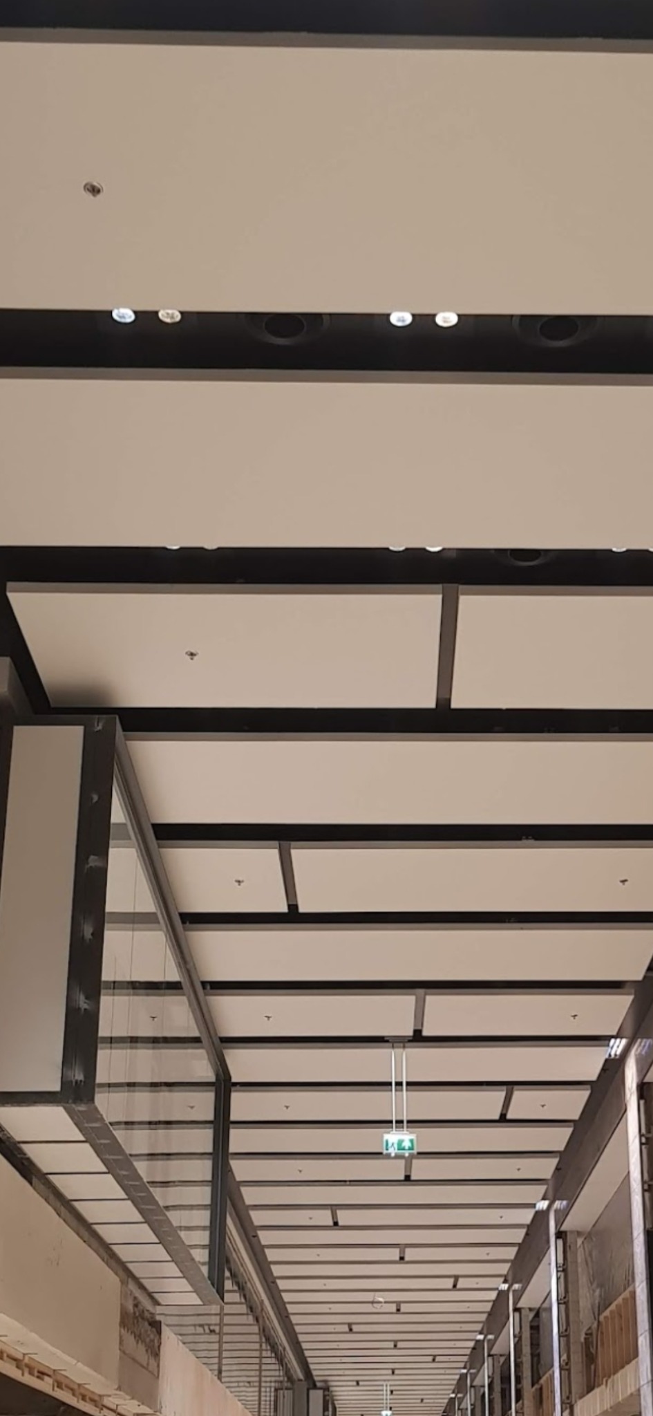 Widok na sufit podwieszany z panelami w obiekcie komercyjnym w Sieprawiu, widoczne oświetlenie i system wentylacji.