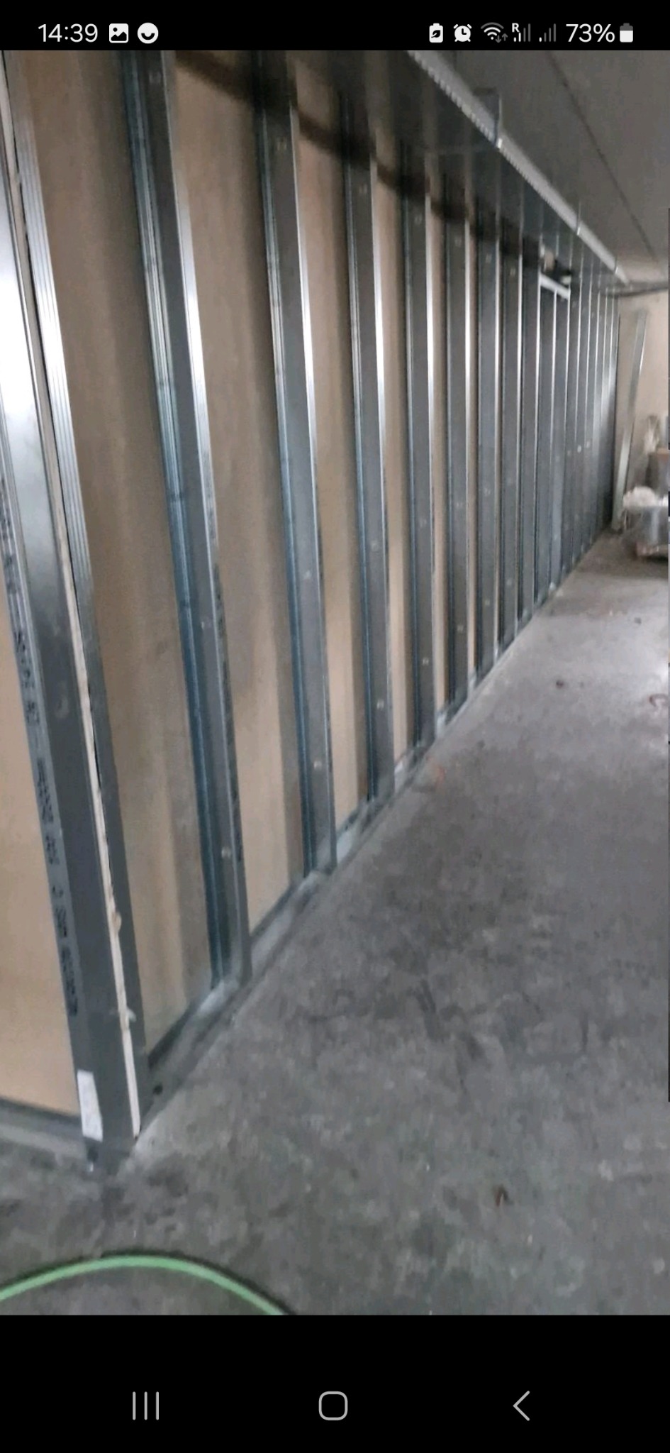 Metalowy stelaż pod zabudowę ścian z płyt, widoczny w trakcie montażu w pomieszczeniu z surowym betonem na podłodze.