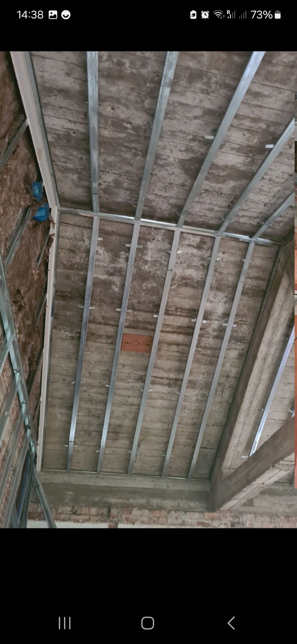 Stelaż z profili metalowych zamontowany na poddaszu, widoczne ocieplenie wełną mineralną, przygotowanie do montażu okładziny.