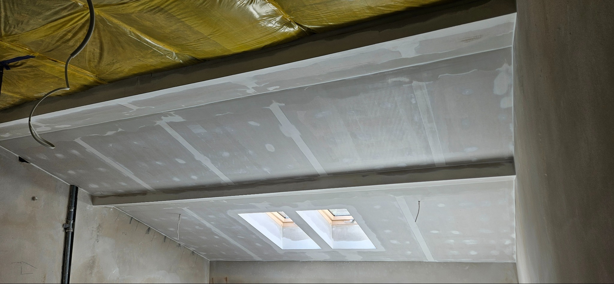 Sufit podwieszany z zamontowaną izolacją i oknem dachowym, wstępnie wyszpachlowany, widoczne łączenia płyt