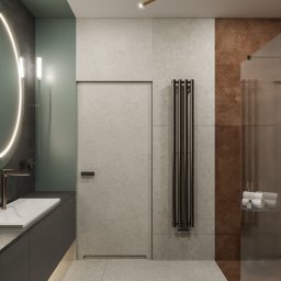 Autorska Pracownia Architektury i Wnętrz Gabriela Radwanowska - Nowoczesna łazienka z okrągłym lustrem podświetlanym LED, ciemnoszarą szafką pod umywalką, pionowym grzejnikiem drabinkowym i minimalistycznym oświetleniem sufitowym.