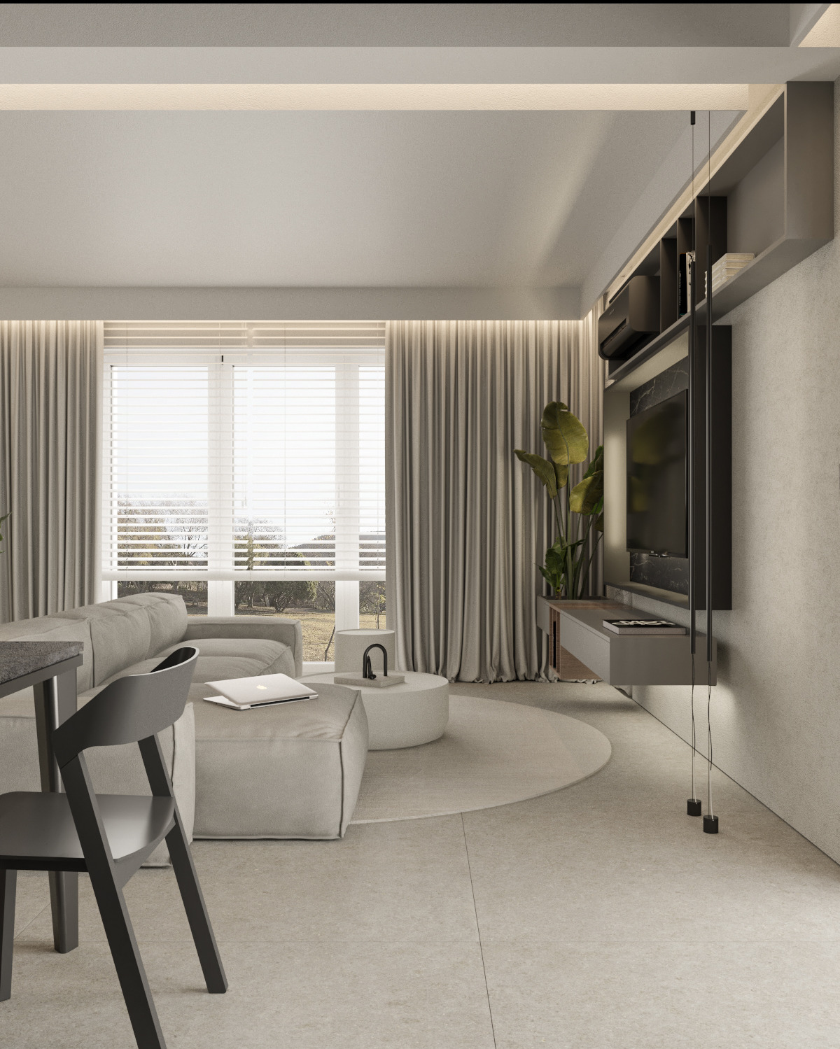 Minimalistyczny salon w neutralnych barwach z szarym narożnikiem, okrągłym dywanem, stolikiem kawowym i wiszącą szafką RTV. Laptop leży na pufie, a czarne krzesło stoi przy blacie.