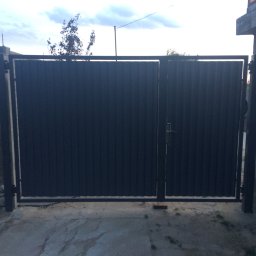 GKDSpaw - Nowoczesna, dwuskrzydłowa brama wjazdowa z blachy trapezowej w kolorze antracytowym, zamontowana na betonowym podjeździe, widok z zewnątrz posesji.