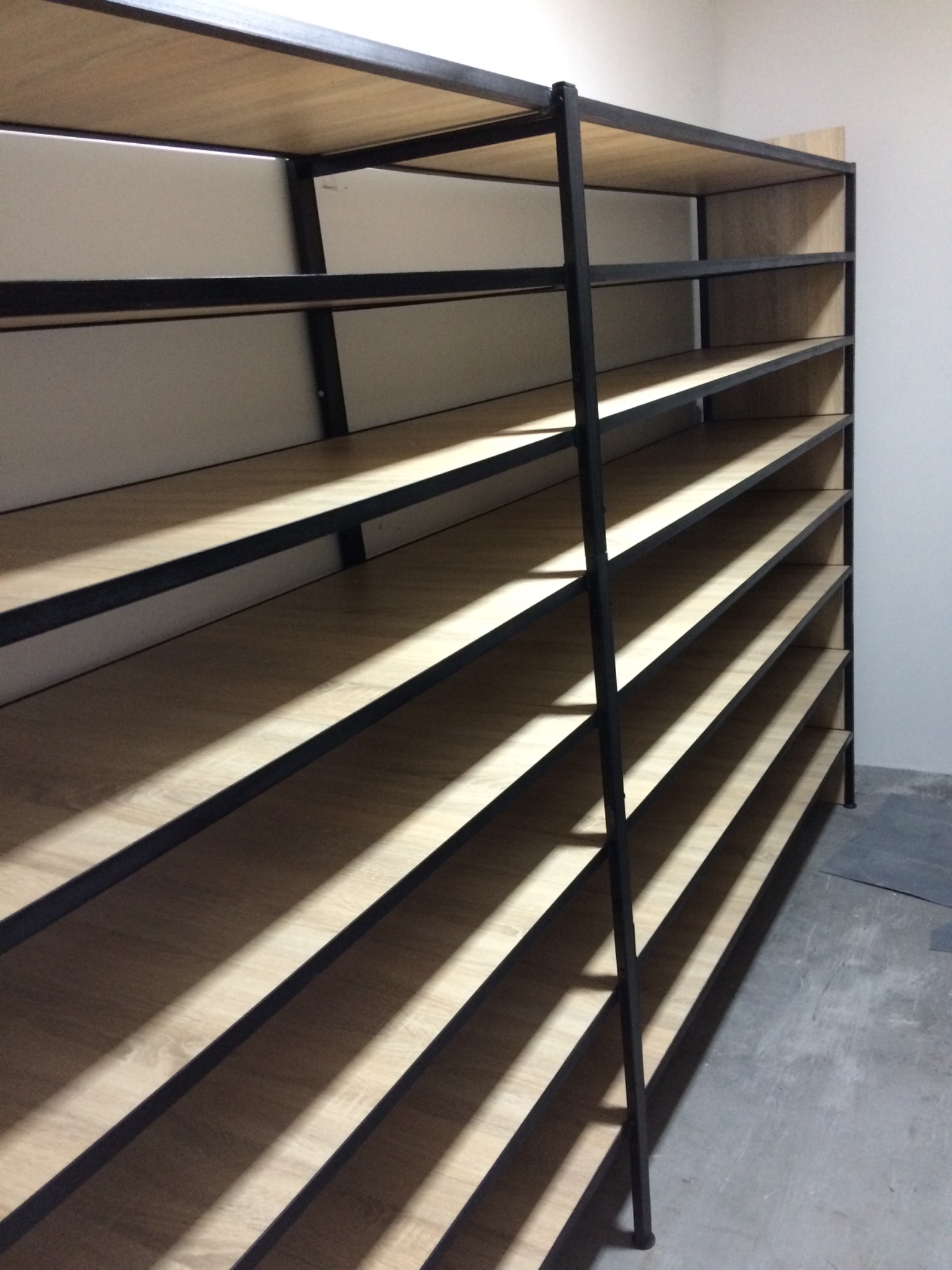 Metalowy regał z drewnianymi półkami, czarna rama, surowe wykończenie, widok z dołu, puste półki.
