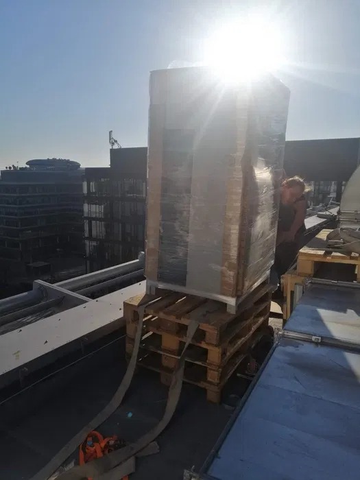 Transport ręczny klimatyzatora na dachu biurowca