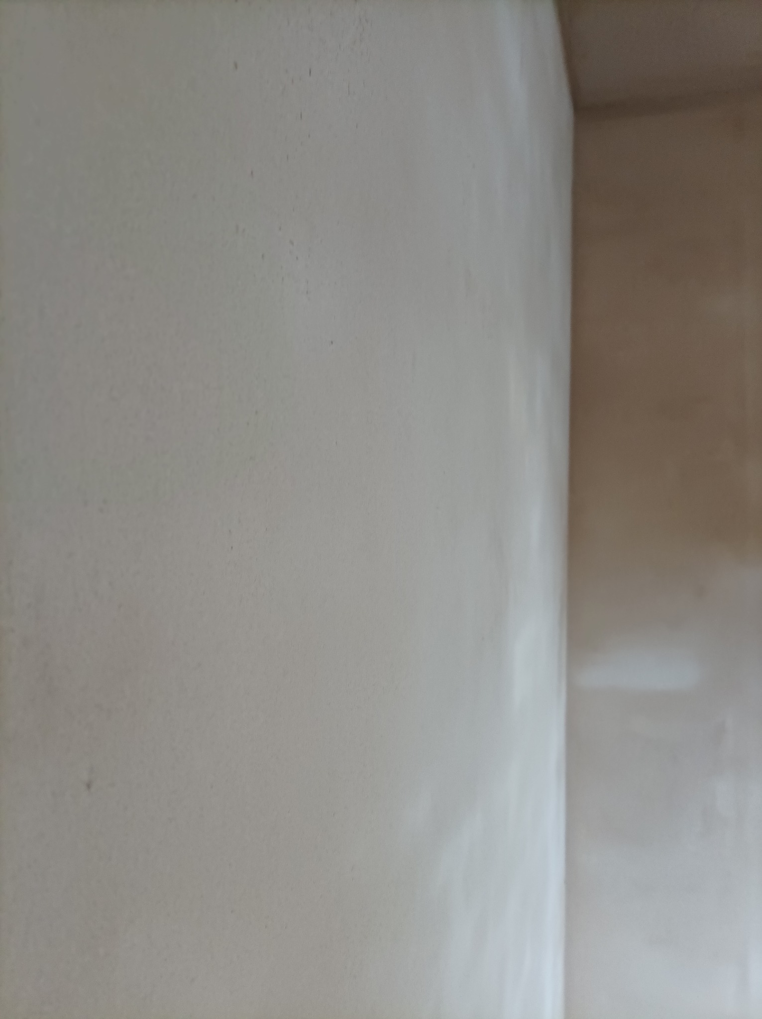 Ściana po nałożeniu gładzi gipsowej, widoczny narożnik. Przygotowanie do malowania w jasnym pomieszczeniu. Delikatna faktura gładzi.