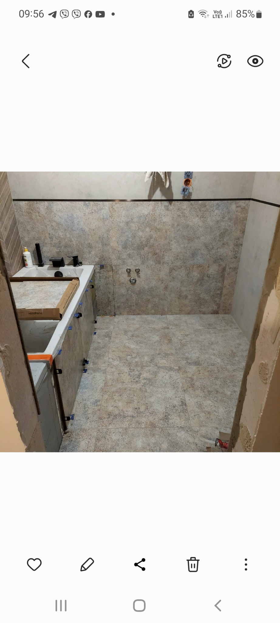 Łazienka w trakcie remontu: ułożone płytki podłogowe i ścienne w beżowych odcieniach, widoczna wanna z zamontowanymi płytkami na obudowie, narzędzia glazurnicze i materiały budowlane.