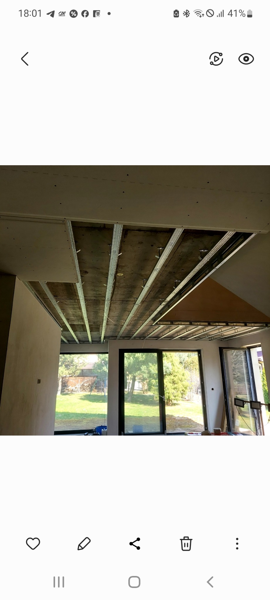 Montaż stelaża sufitu podwieszanego z płyt g-k w jasnym pomieszczeniu z dużymi oknami. Widoczne profile i konstrukcja nośna.