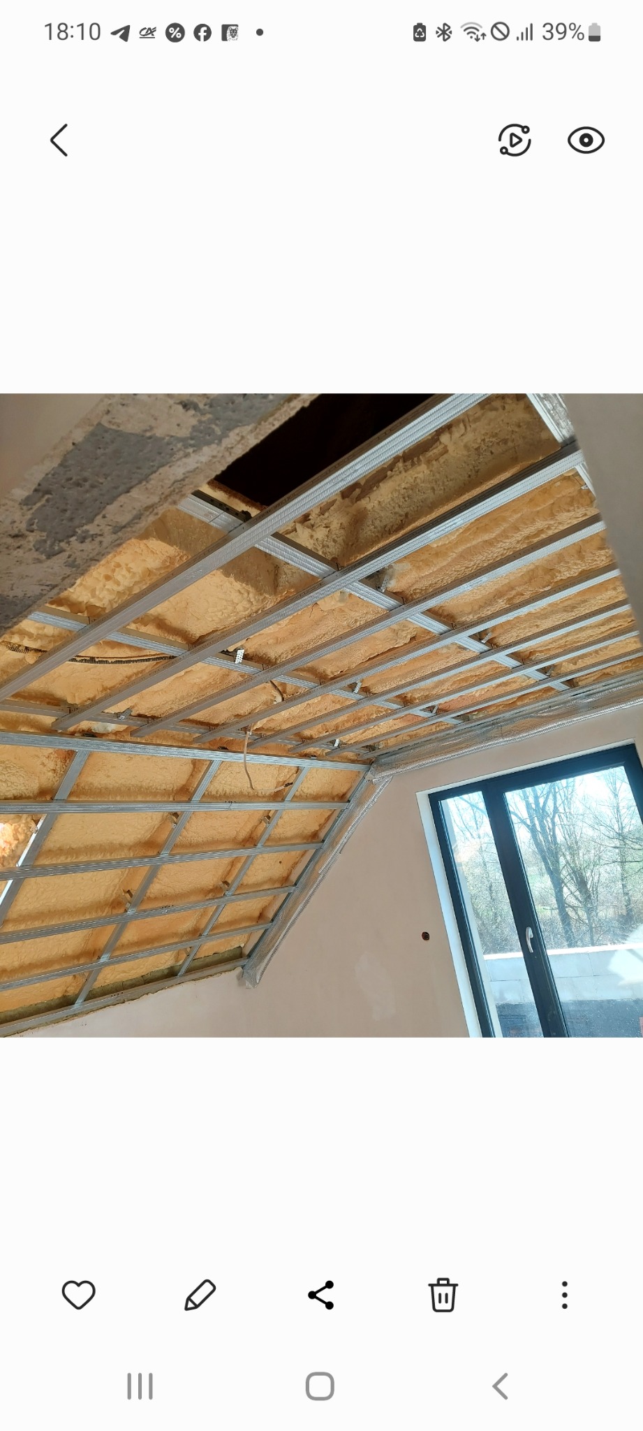 Sufit podwieszany z metalowym stelażem i izolacją z pianki, widoczne okno i fragment ściany. Stelaż przygotowany pod płyty gipsowe.