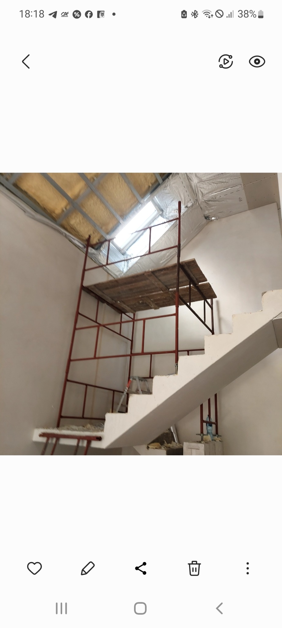 Skośny sufit z izolacją i rusztowaniem w pokoju ze schodami. Prace wykończeniowe w trakcie. Widok na okno dachowe.