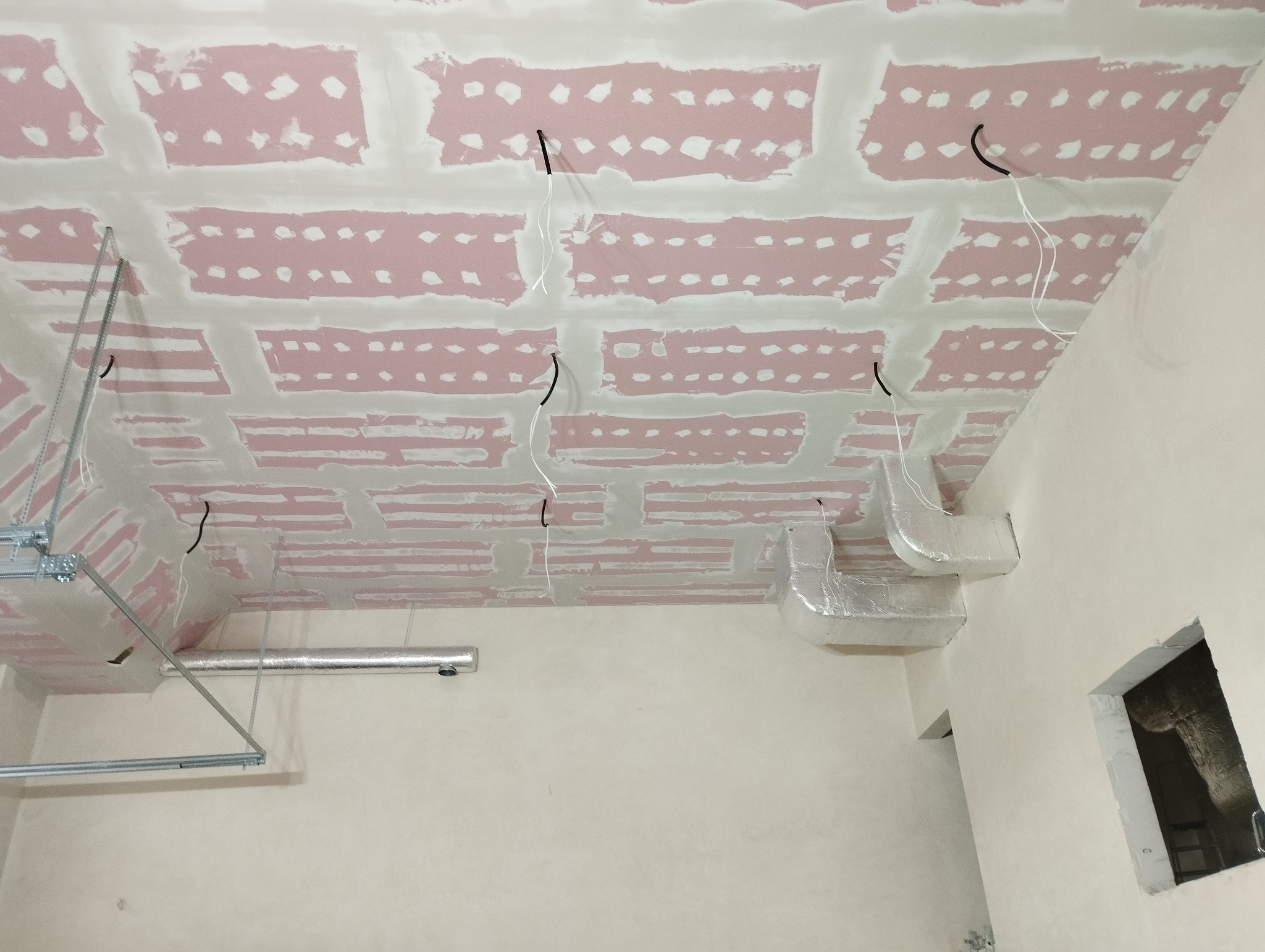 Niedokończony sufit z płyt kartonowo-gipsowych z widocznymi przewodami elektrycznymi i elementami wentylacji, przed nałożeniem gładzi.