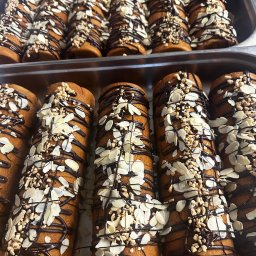 TASTY CATERING Tomasz Szmidt - Ręcznie dekorowane babeczki w metalowej formie, polane czekoladą i posypane płatkami migdałów oraz orzechami, gotowe do serwowania na przyjęciu.