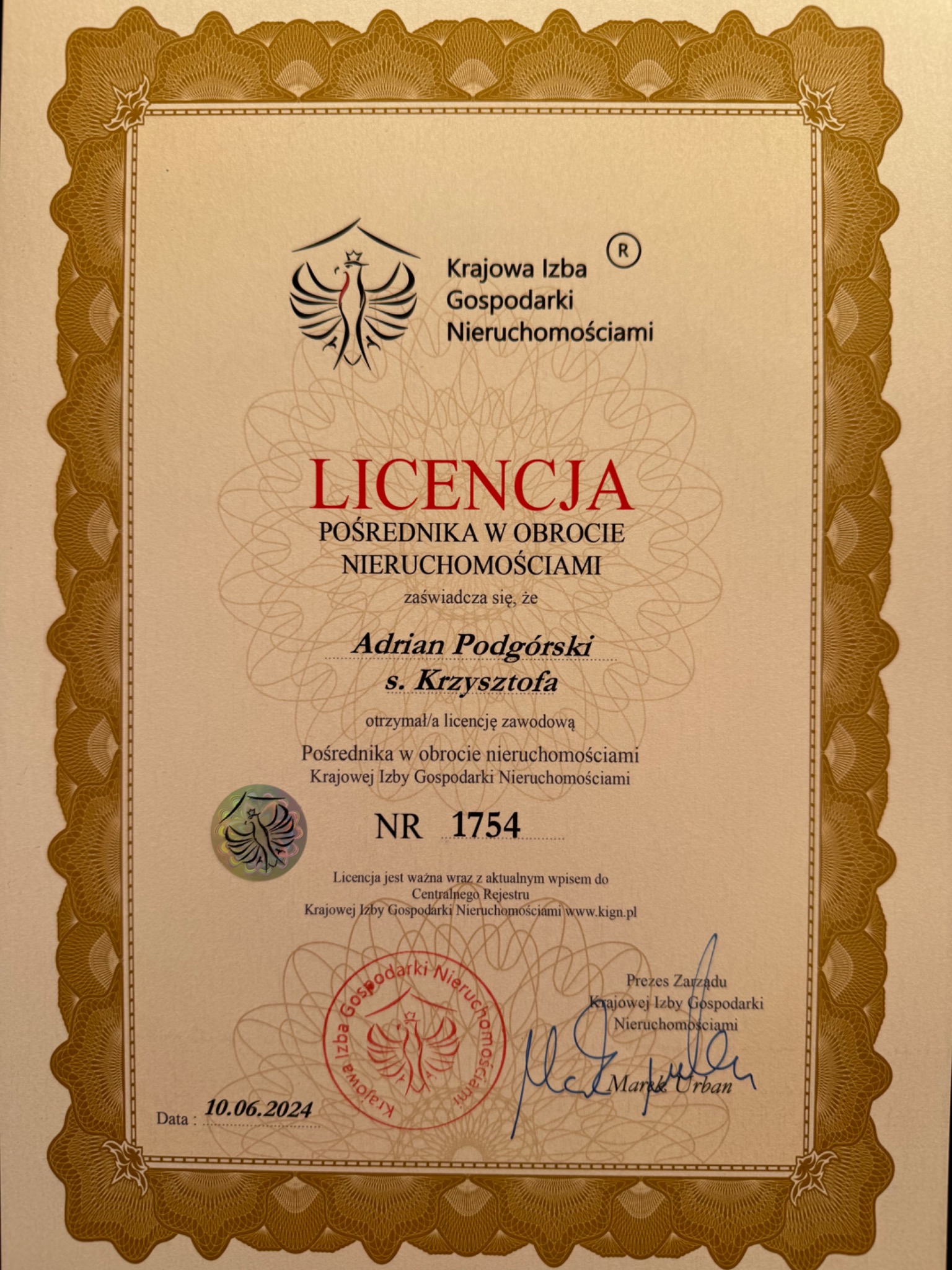 Skan licencji pośrednika w obrocie nieruchomościami, wydanej przez Krajową Izbę Gospodarki Nieruchomościami, z datą 10.06.2024 i podpisem Prezesa Zarządu Marka Urbana, w ozdobnej ramce.