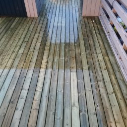 Karol P - Impregnowany drewniany taras z widoczną różnicą w kolorze po częściowym nałożeniu preparatu, biała balustrada w tle.