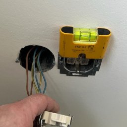 ELEKTRO-TOM - Elektryk montuje gniazdko elektryczne w ścianie, używając poziomicy Stabila do precyzyjnego ustawienia.