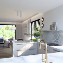 Jasna kuchnia z wyspą i złotą armaturą. Minimalistyczny design z marmurowym blatem i roślinami. Widok na salon i ogród przez okno.