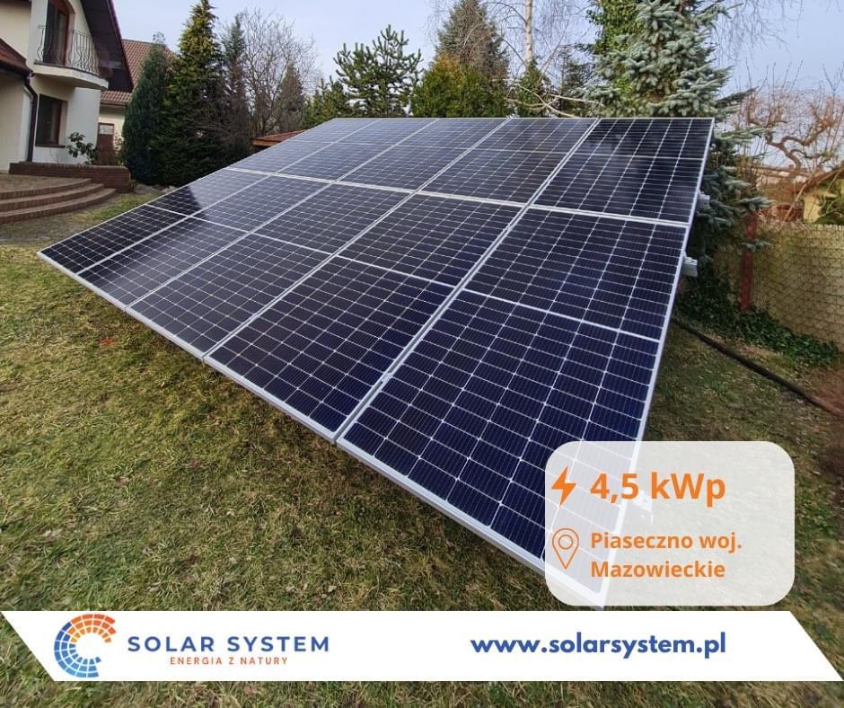 Instalacja paneli słonecznych 4,5 kWp na trawniku przed domem jednorodzinnym, z logo firmy Solar System i adresem strony internetowej.