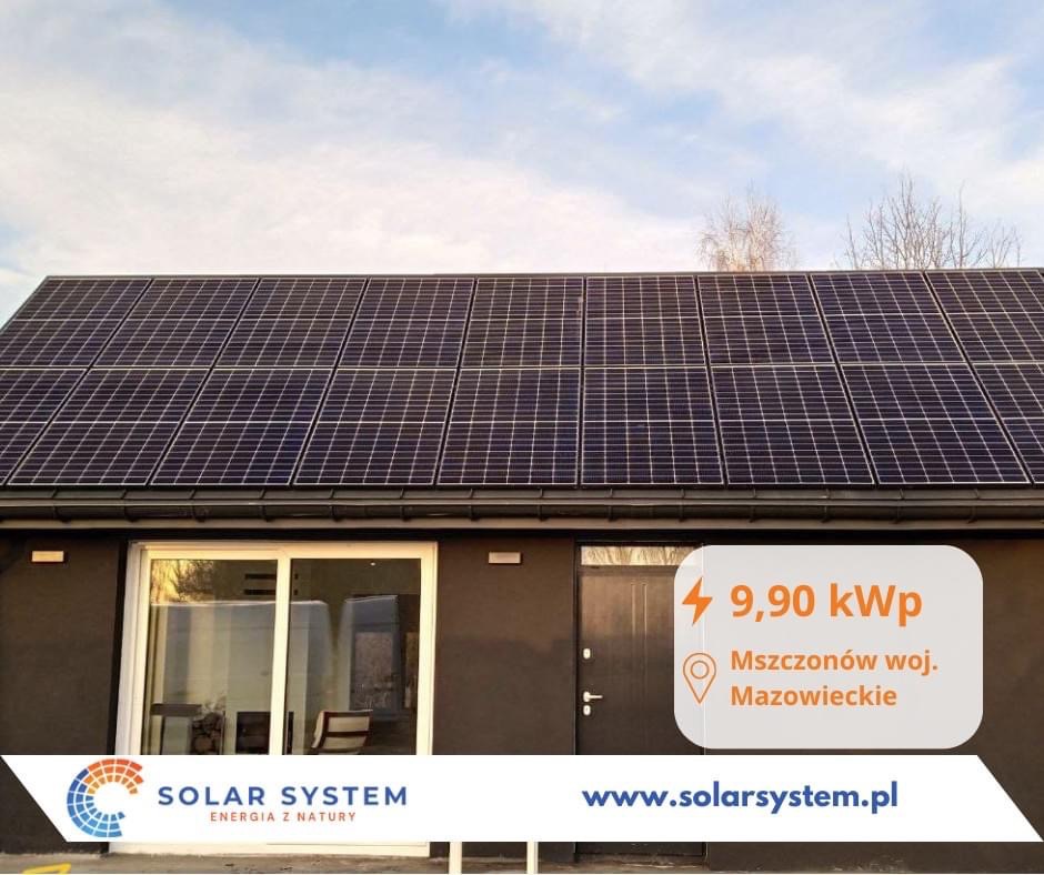 Czarny budynek z panelami słonecznymi na dachu, widoczne okno przesuwne i drzwi wejściowe, informacja o mocy instalacji 9,90 kWp oraz lokalizacji Mszczonów, woj. Mazowieckie, logo Solar System.