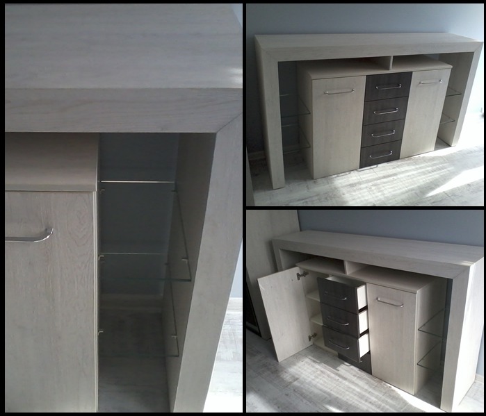 Komoda w kształcie litery U z jasnego drewna z szufladami w kolorze grafitowym, z przeszklonymi półkami po bokach, uchylone drzwiczki ukazują wnętrze szafki.