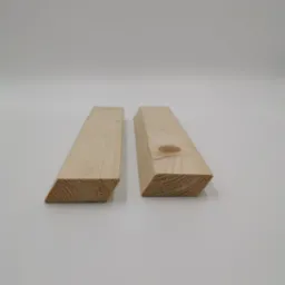 Dwa kawałki świeżo obrobionego drewna iglastego, oba z ukośnie ściętym końcem, leżące na białym tle. Jeden kawałek ma widoczny sęk.