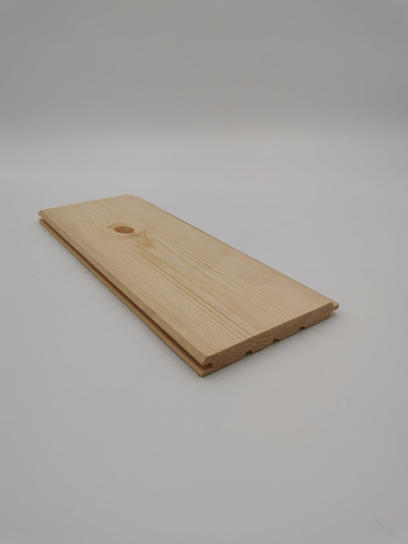 Profilowana deska z jasnego drewna z widocznym usłojeniem i sękiem, przeznaczona do łączenia na pióro i wpust.
