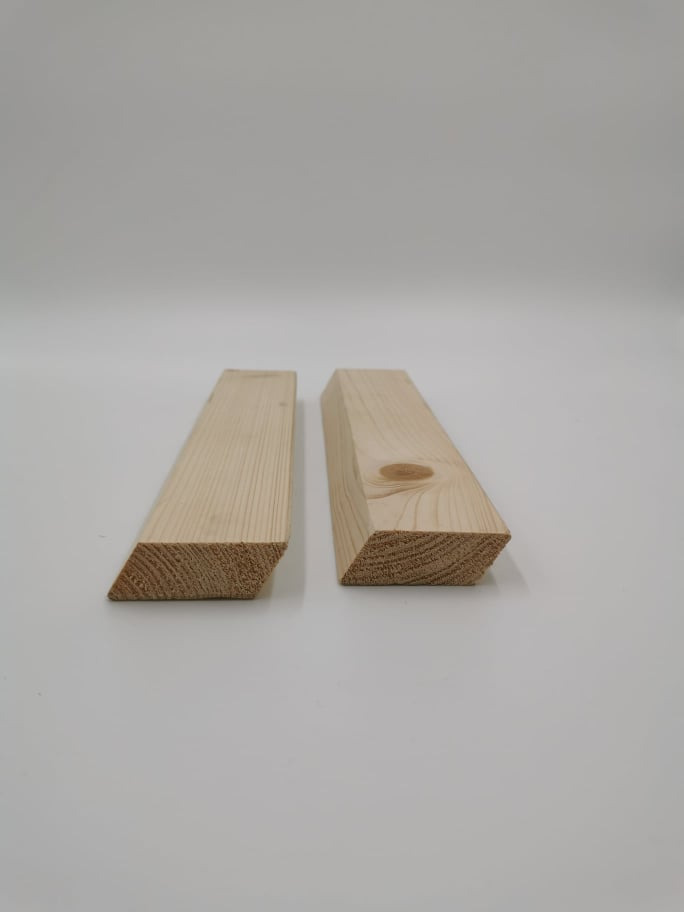 Dwa kawałki świeżo obrobionego drewna iglastego, oba z ukośnie ściętym końcem, leżące na białym tle. Jeden kawałek ma widoczny sęk.