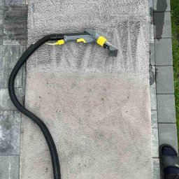 VitLen- Clean Olena Cherkashyna - Szary dywanik czyszczony parowo na zewnątrz, widoczna różnica w kolorze po czyszczeniu, czarne obuwie w rogu kadru.