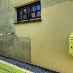 VitLen- Clean Olena Cherkashyna - Mycie elewacji domu z żółtą fasadą za pomocą myjki ciśnieniowej. Widoczny fragment elewacji przed i po czyszczeniu, okno z brązową ramą i żółta skrzynka gazowa.