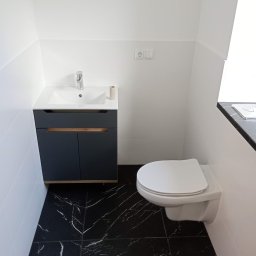 Volodymyr Andrushchak - Nowoczesna łazienka z czarną marmurową podłogą, białymi płytkami ściennymi i wiszącą toaletą. Szafka pod umywalką w kolorze grafitowym z drewnianymi akcentami.