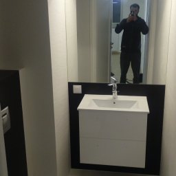 Volodymyr Andrushchak - Nowoczesna, minimalistyczna łazienka w bieli i czerni. Umywalka z szafką, toaleta podwieszana, duże lustro z odbiciem osoby robiącej zdjęcie. Oświetlenie LED.