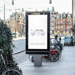 Plakat reklamowy NHS na przystanku autobusowym w Amsterdamie, przedstawiający schematyczny rysunek samochodu w kolorze fioletowym.