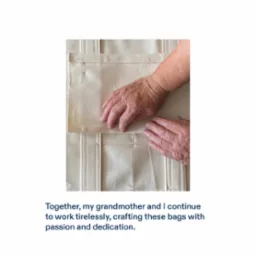 Ręce układają fragmenty beżowej, płóciennej torby w trakcie szycia, widoczne szwy i pojedyncza szpilka.