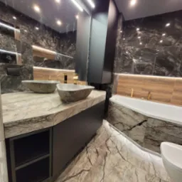Elegancka łazienka z marmurowymi płytkami, kamiennymi umywalkami i podświetleniem LED pod wanną.