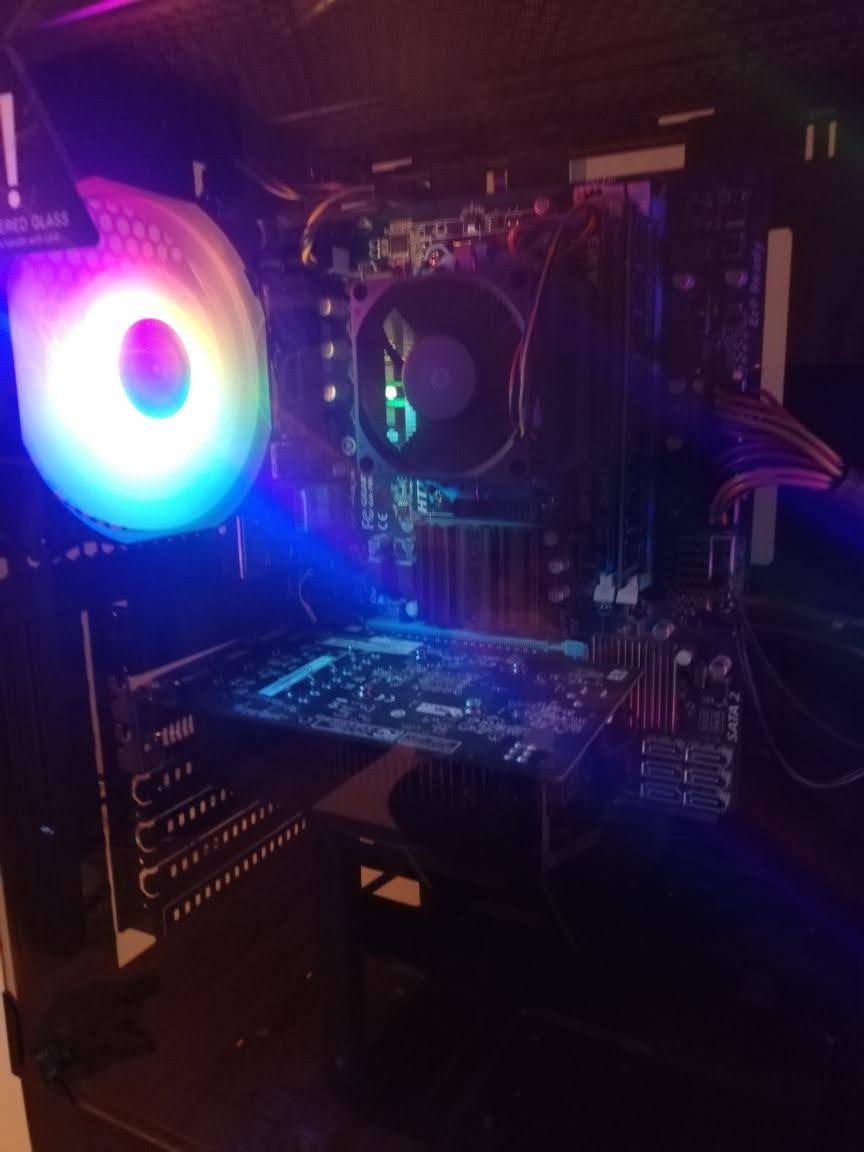 Wnętrze komputera stacjonarnego z podświetlanym wentylatorem procesora i kartą graficzną, widok z boku przez szybę obudowy.
