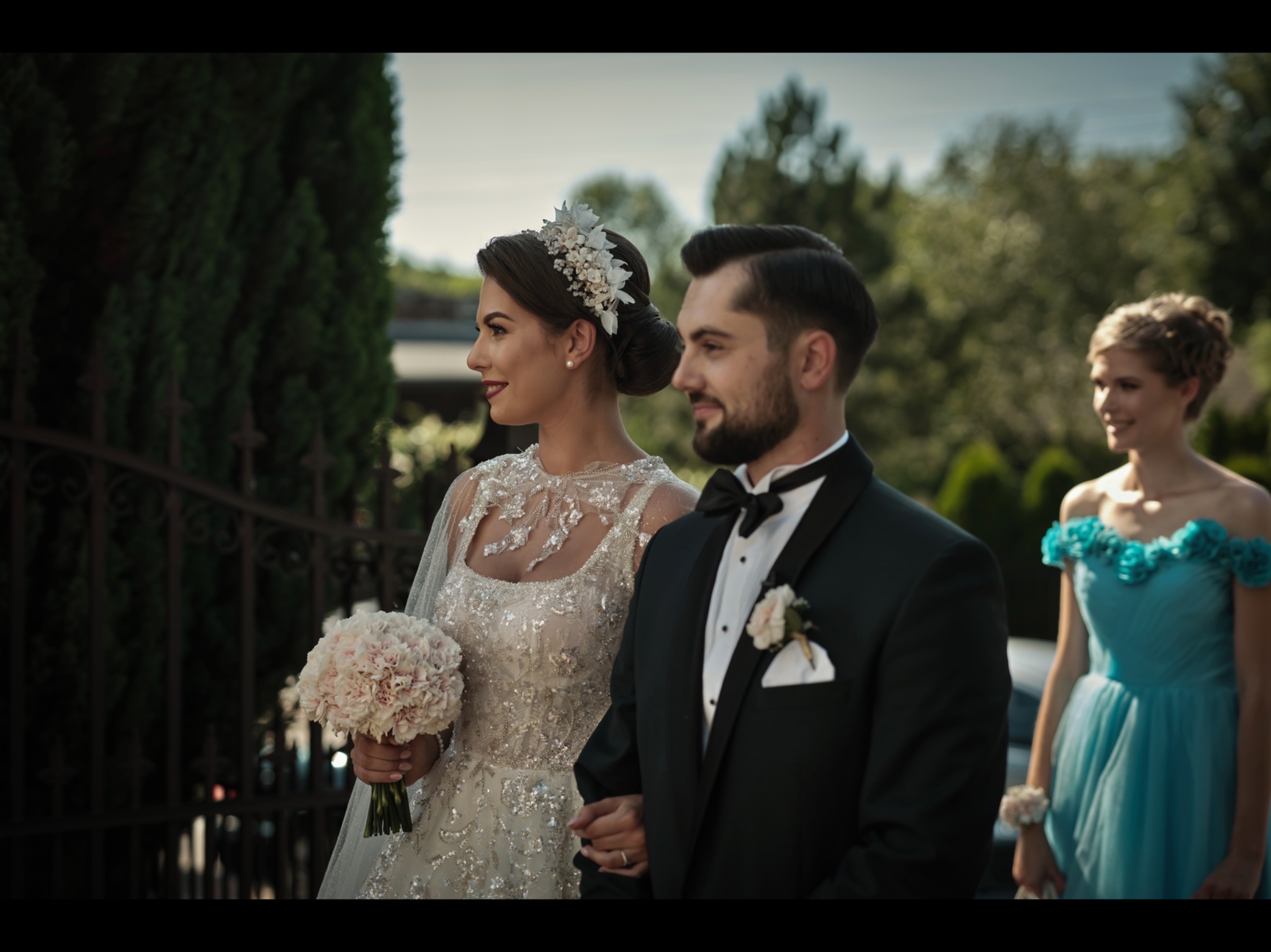 Elegancka para młoda, panna młoda trzyma bukiet, druhny w tle, zdjęcie z pleneru ślubnego.