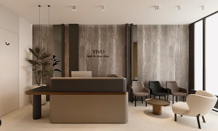 Recepcja w nowoczesnym salonie fryzjersko-kosmetycznym z logo 'VIVO', marmurowa ściana, minimalistyczne krzesła w strefie oczekiwania i wysoka roślina doniczkowa.