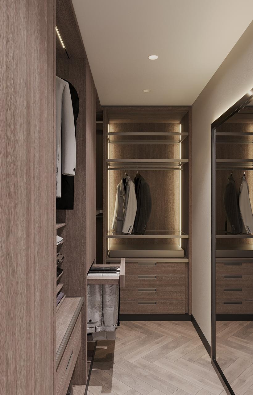 Nowoczesna garderoba z drewnianymi szafami, szufladami i oświetleniem LED, widoczne ubrania wiszące i złożone w szufladach, parkiet w jodełkę na podłodze, lustrzane drzwi szafy.
