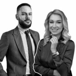 Portret dwojga prawników z Gdańska: mężczyzna w szarym garniturze i kobieta w ciemnej bluzce, oboje uśmiechnięci na białym tle.