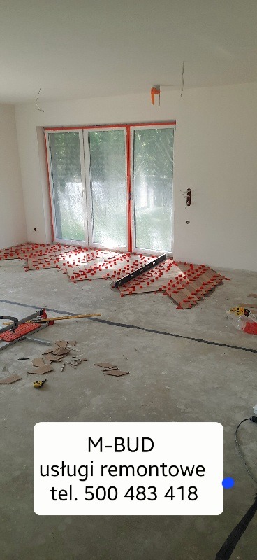 Układanie paneli z użyciem systemu poziomowania płytek w jasnym pomieszczeniu z dużym oknem; widoczne narzędzia i resztki paneli.