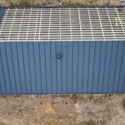 Widok z góry na częściowo pokryty, ciemnoszary blachodach na nowo budowanym domu; widoczna więźba dachowa na pozostałej części dachu.