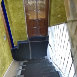 Oleksandr Misiiuk - Schody i ściana zabezpieczone folią malarską przed malowaniem, widoczne naklejone taśmy ochronne, drzwi również zakryte folią.